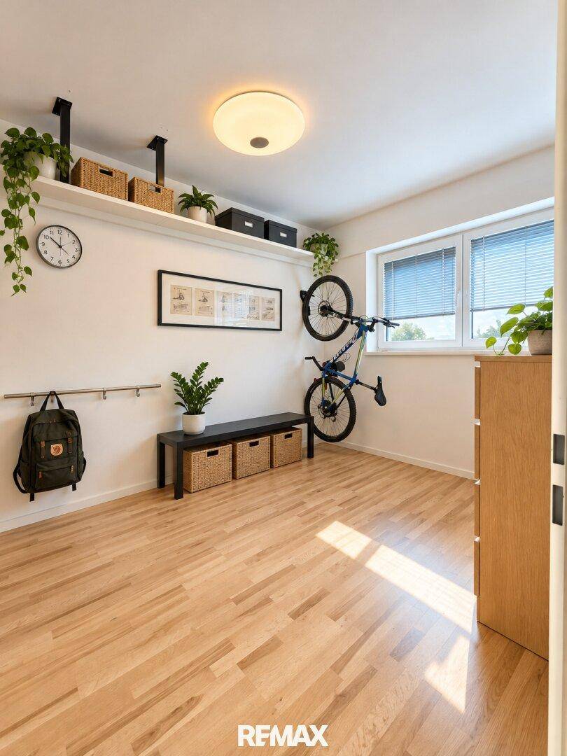 Helles Zimmer mit Holzfußboden, Wandregalen und viel Tageslicht.