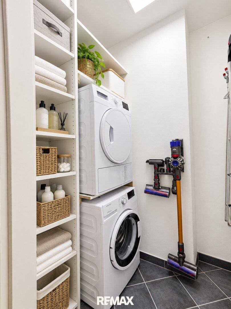 Praktischer Hauswirtschaftsraum mit Waschmaschine, Trockner und Regalsystem.