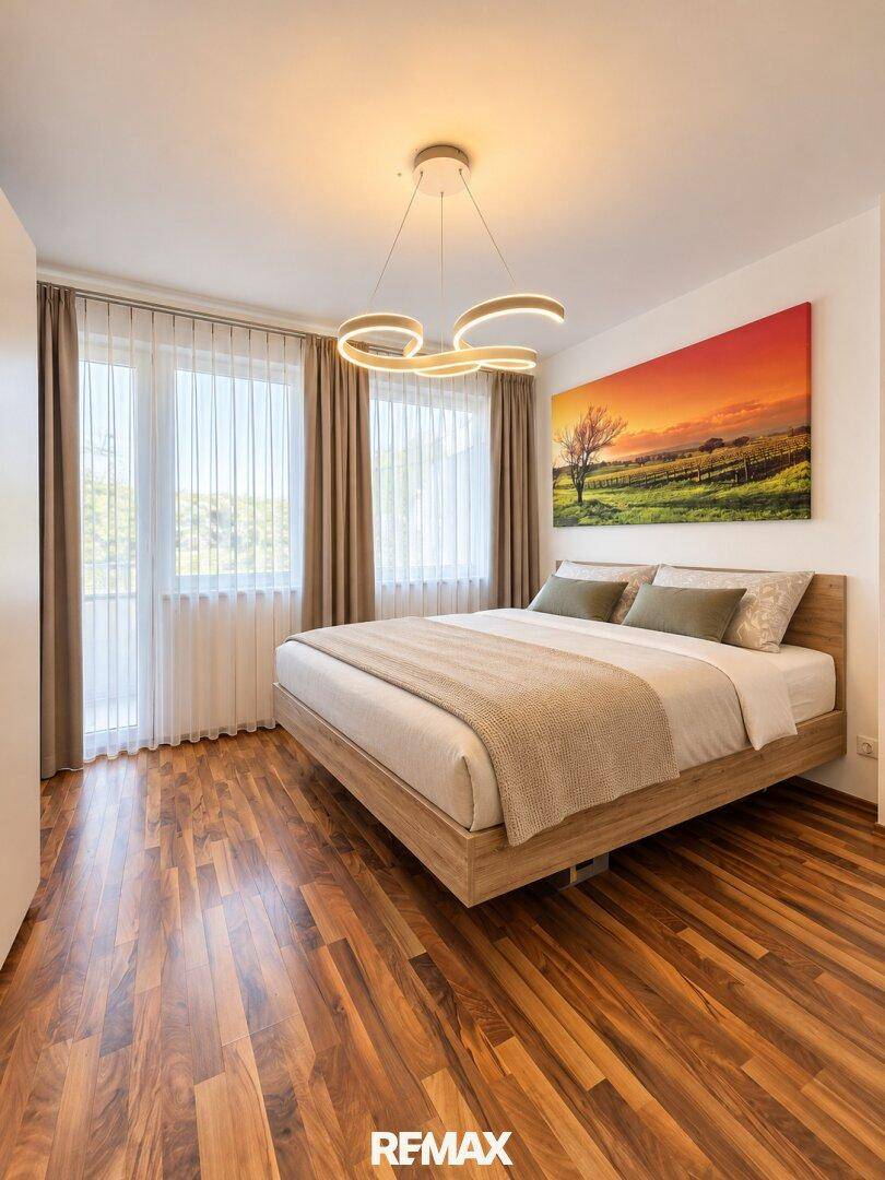 Helles Schlafzimmer mit Holzboden, großem Bett und Zugang zum Balkon.