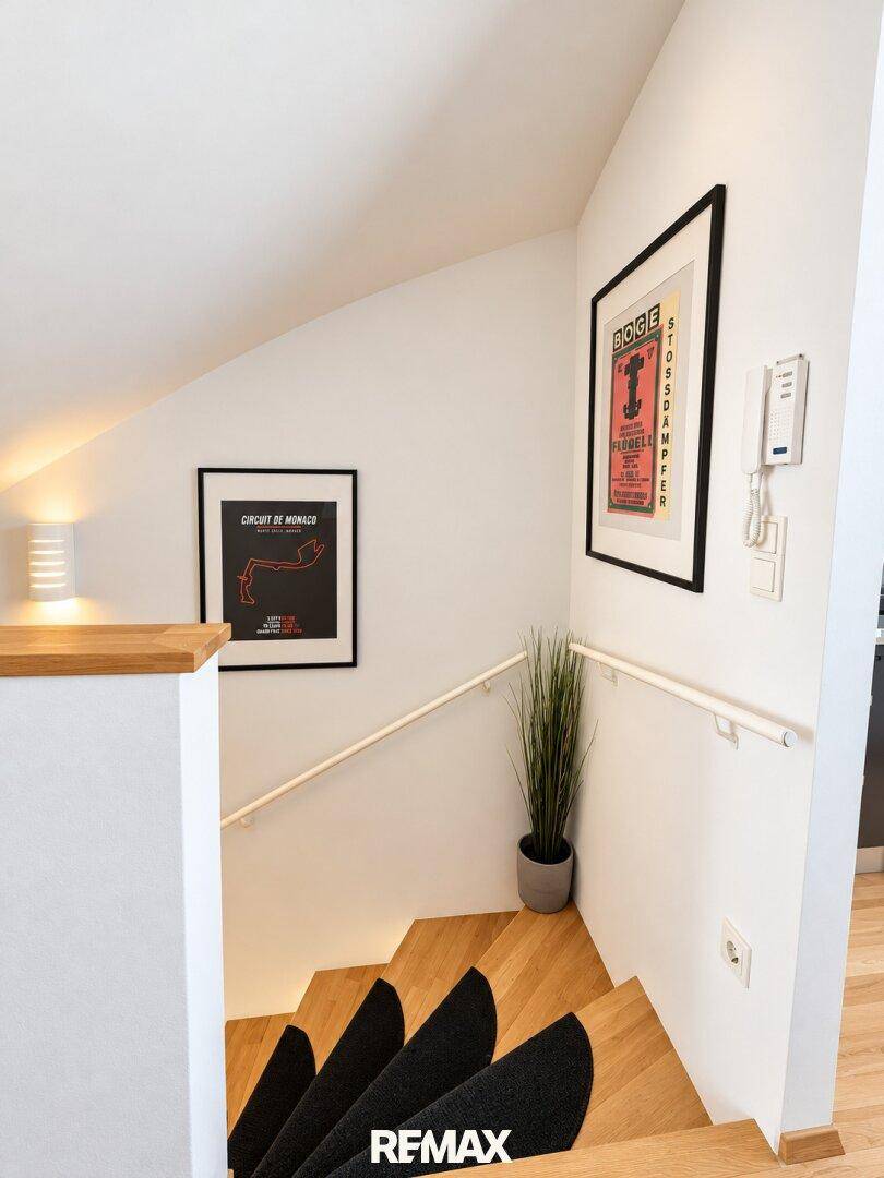 Treppenaufgang mit Holzstufen, modernem Geländer und Wanddekoration.