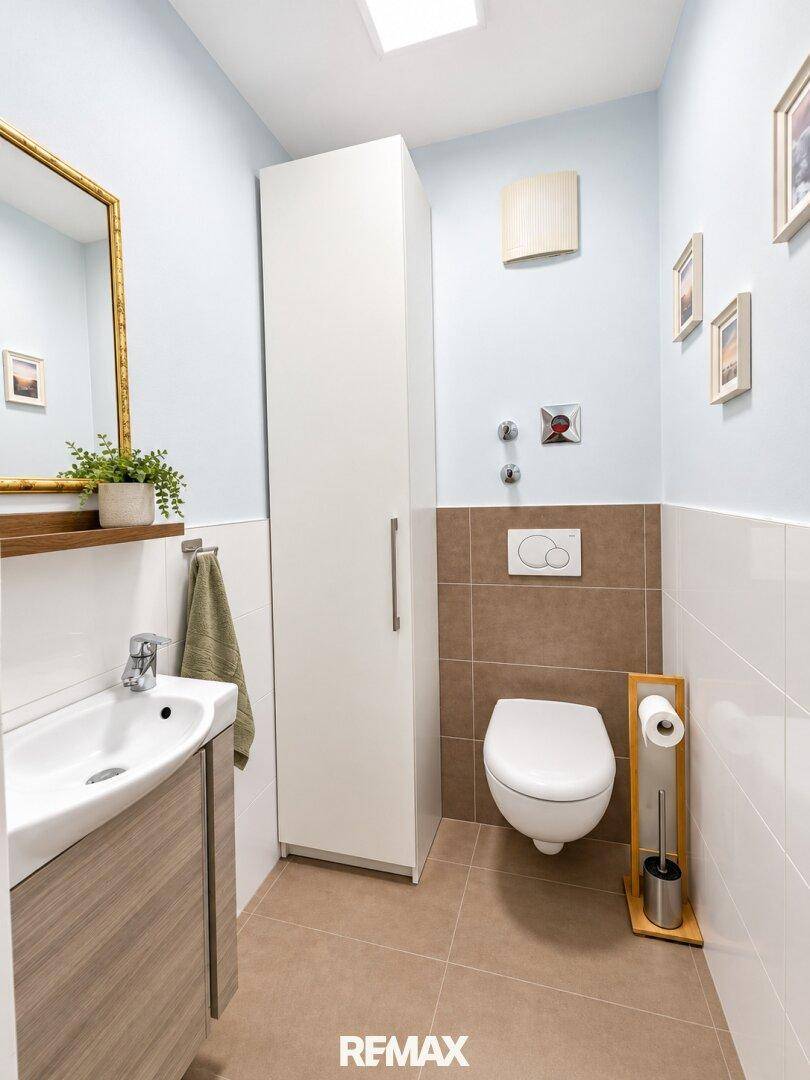 Modernes Gäste-WC mit wandhängendem WC, Waschbecken und Spiegel.