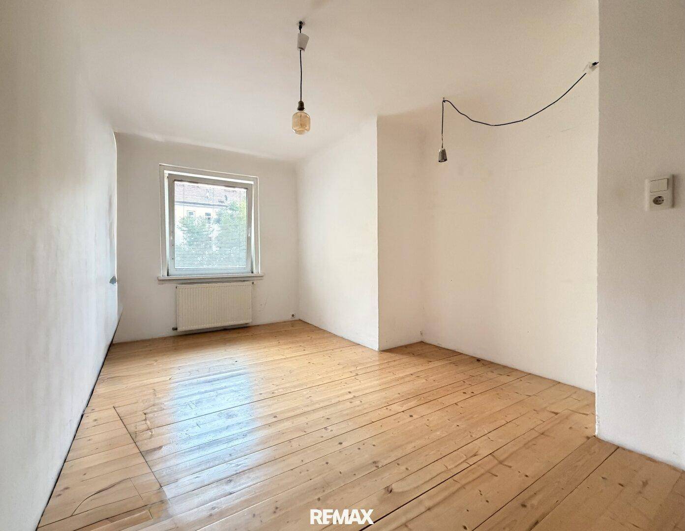 Leerer Raum mit Holzdielenboden und Fenster, bietet Potenzial für individuelle Einrichtung.