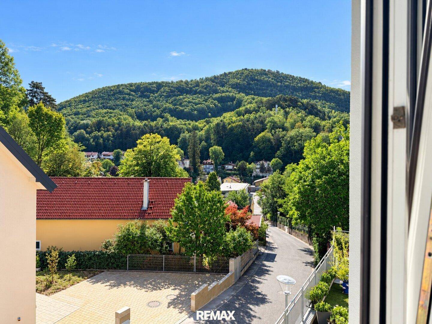 Aussicht aus einem Fenster auf die grüne Umgebung und bewaldete Hügel.