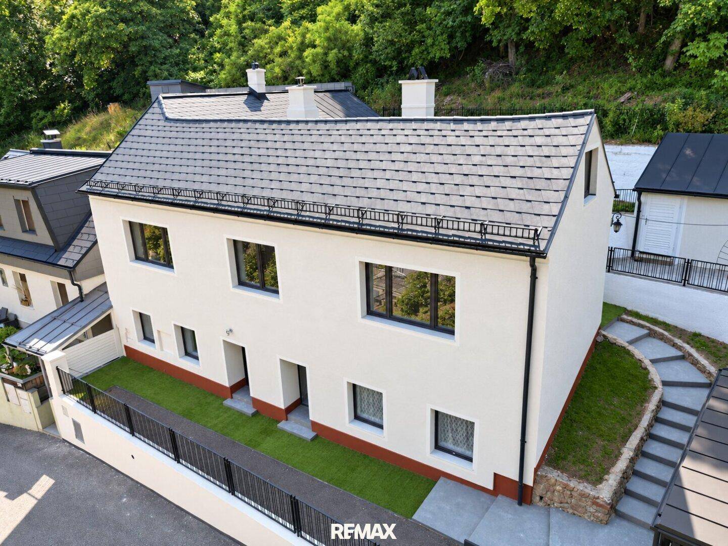 Luftaufnahme des modernen Wohnhauses mit weißer Fassade und dunklem Satteldach.