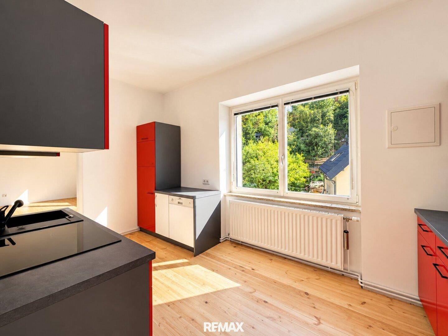 Helle Küche mit Fenster, Heizkörper und Ausblick auf die grüne Umgebung.