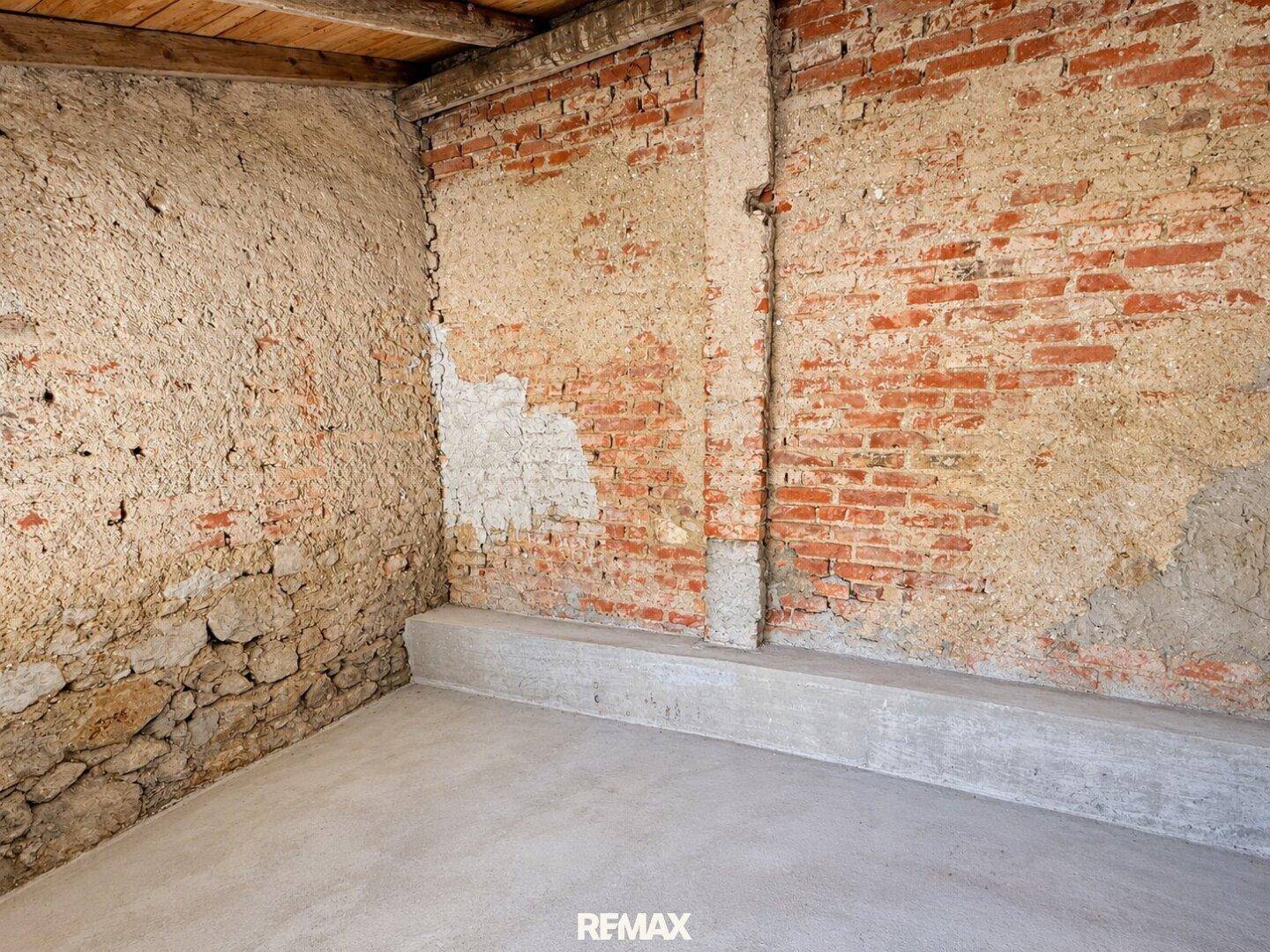 Unfertiger Kellerraum mit freigelegten Ziegelwänden und neuem Betonboden, bereit für den Ausbau.