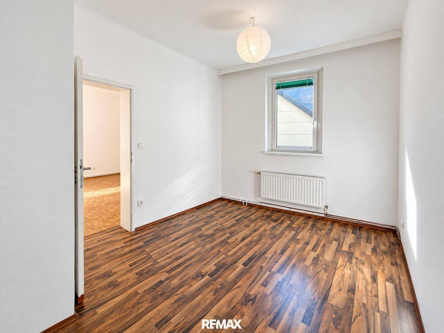 Helles Zimmer mit Laminatboden und weiß gestrichenen Wänden, bereit zur individuellen Gestaltung.
