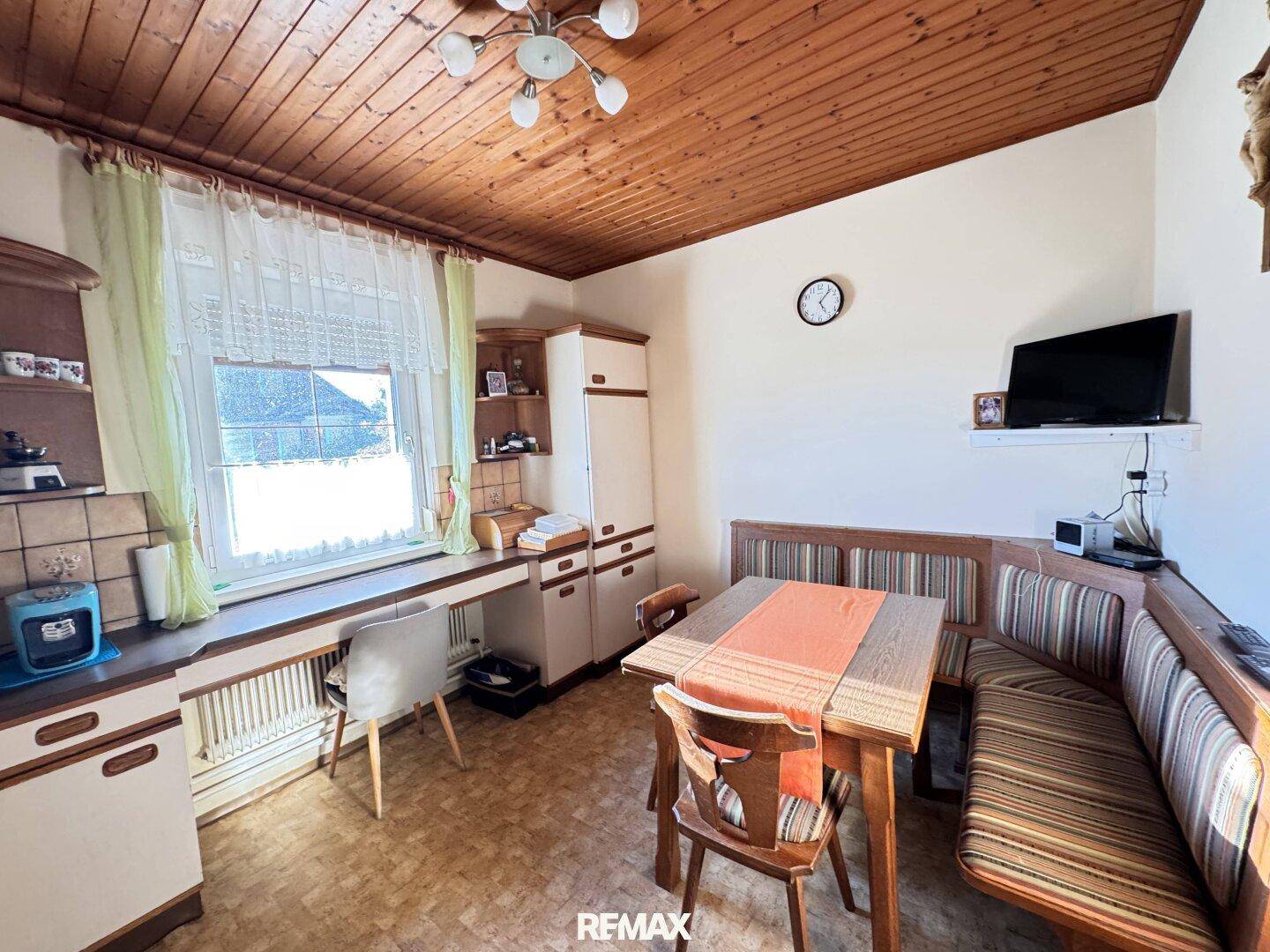 Gemütliche Wohnküche mit Holztäfelung an der Decke und traditioneller Eckbank.