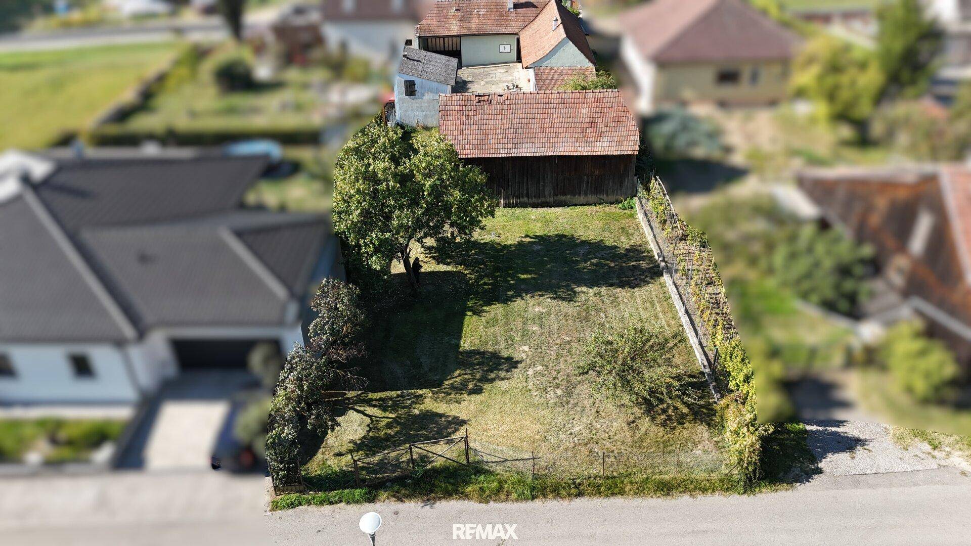 Luftaufnahme eines großen Gartengrundstücks mit Rasenfläche und Baumbestand hinter dem Haus.