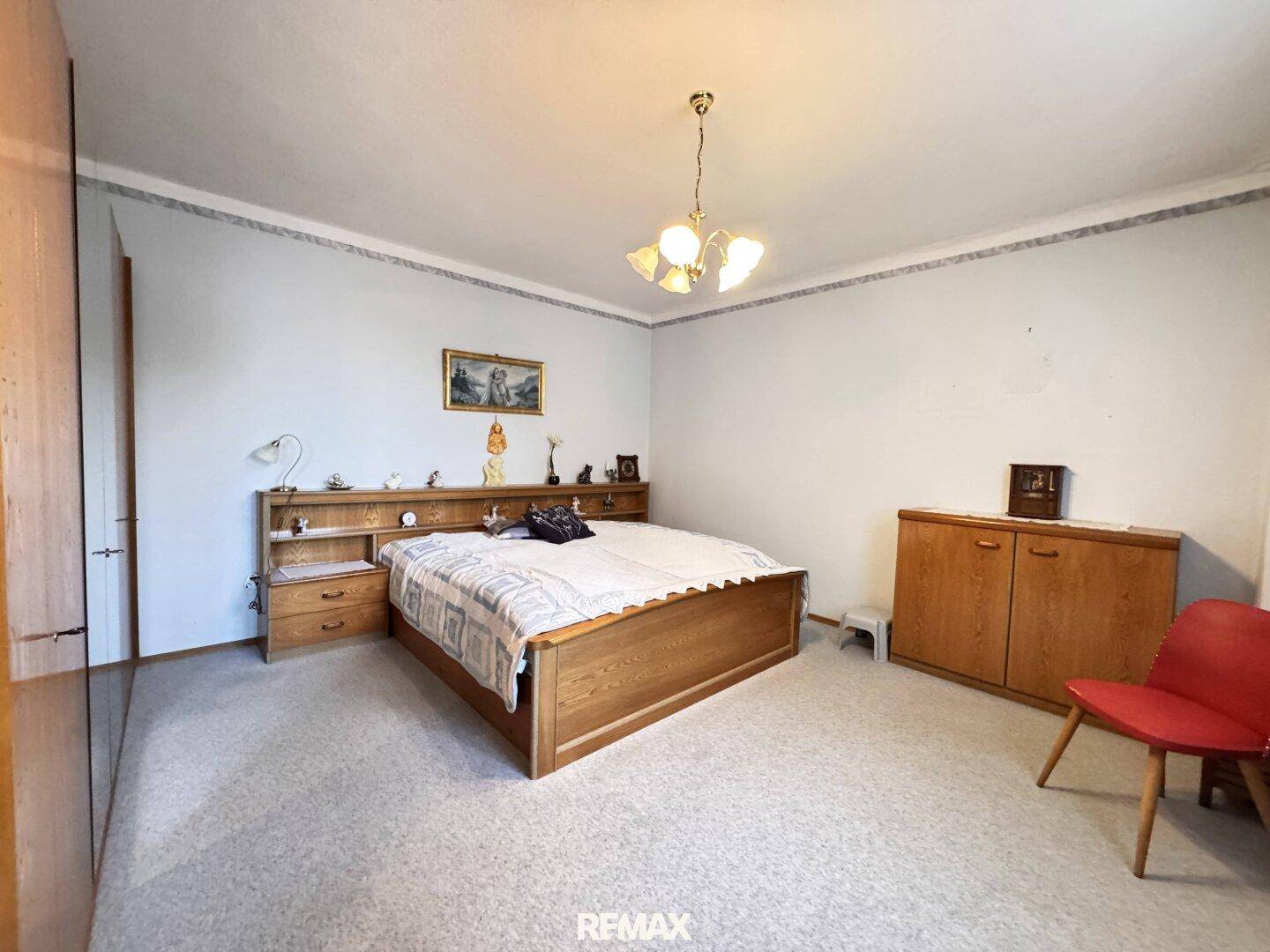 Schlafzimmer mit Doppelbett, Holzmöbeln und Teppichboden in einem traditionellen Stil.