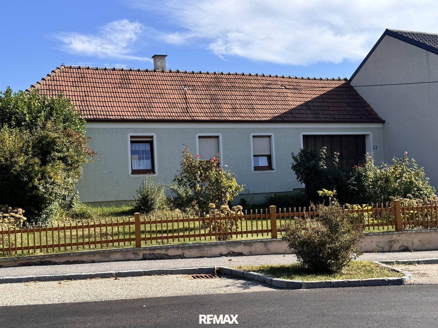 Vorderansicht des Einfamilienhauses von der Straße aus mit Vorgarten und Zaun.