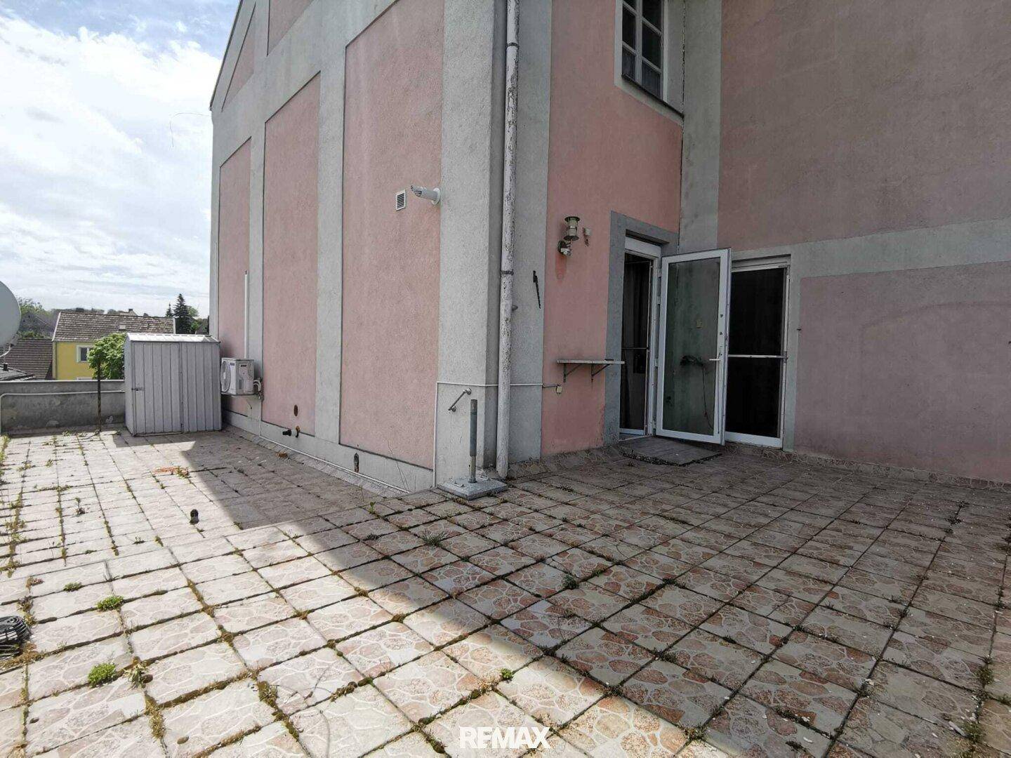 Geräumige Terrasse mit Fliesenboden und Zugang zum Gebäude.