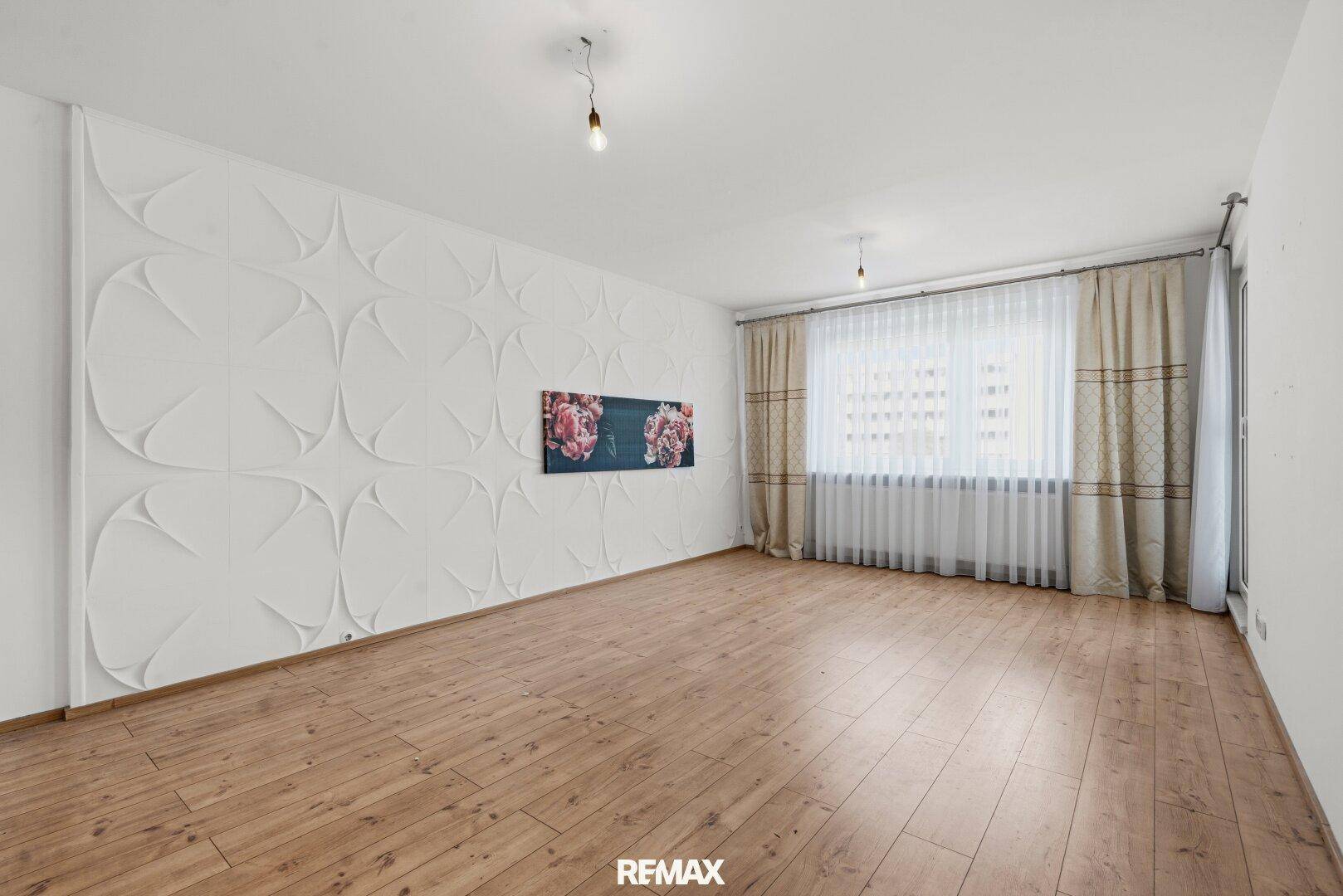 Geräumiger Wohnbereich mit heller Holzoptik und einer modern gestalteten Akzentwand.