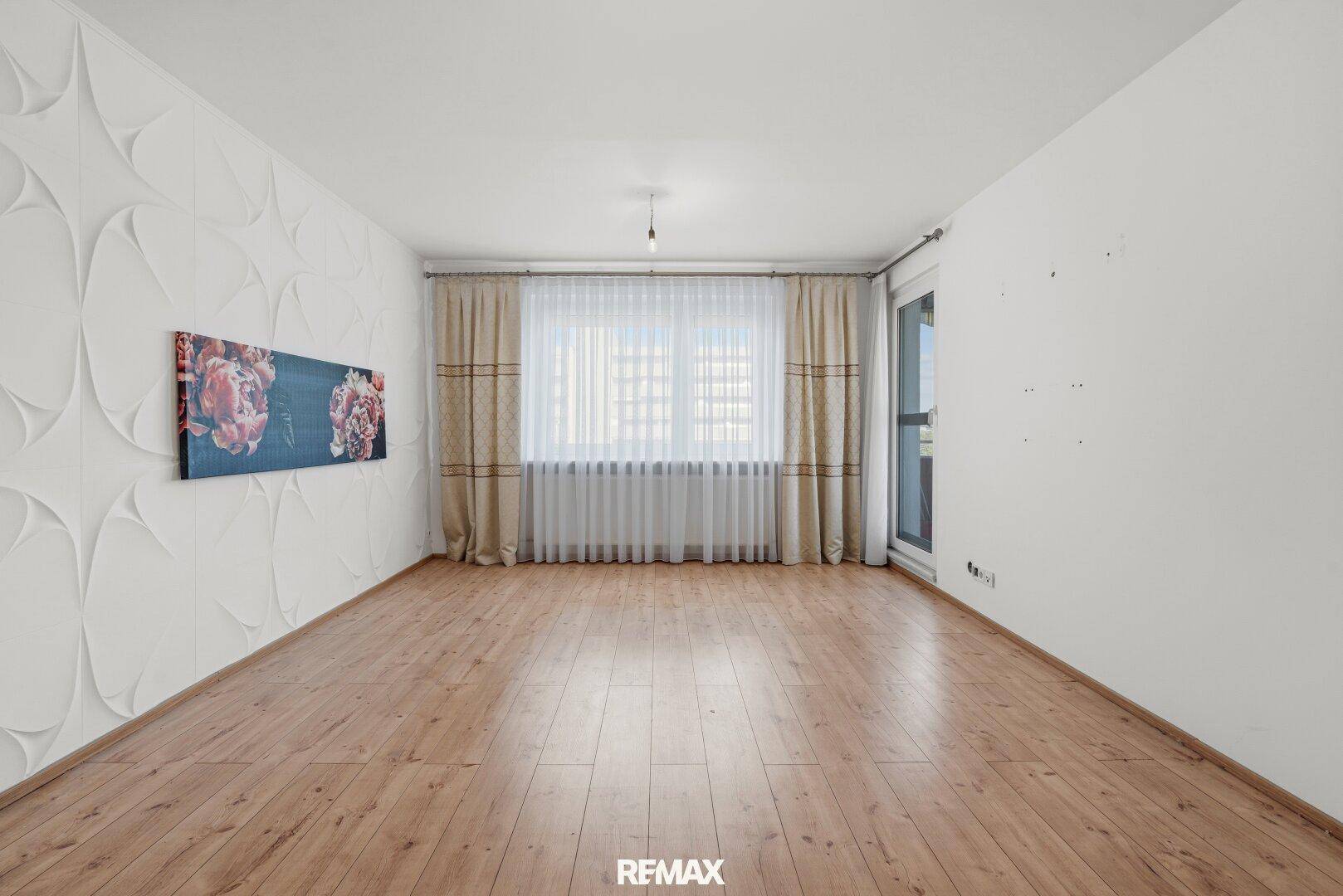 Leerer Wohnraum mit dekorativer Wandgestaltung, Holzfußboden und großem Fenster.