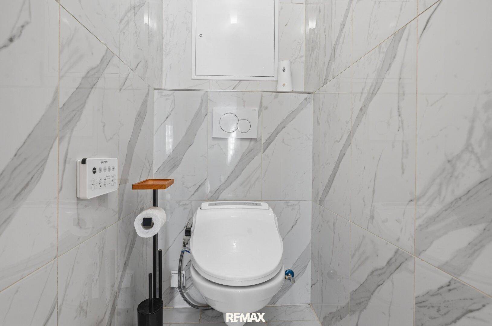 Modernes WC mit wandhängender Toilette, Bidetfunktion und eleganten Marmorfliesen.