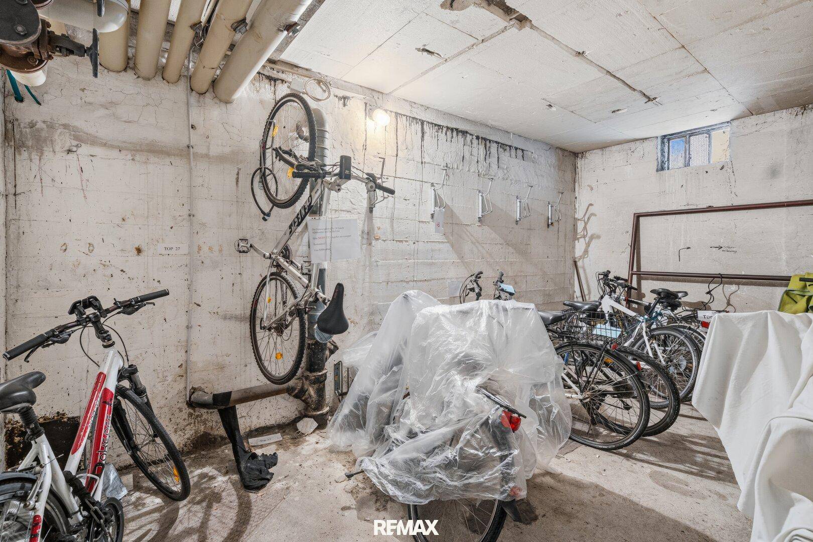 Fahrradraum im Keller mit mehreren abgestellten Fahrrädern und Betonwänden.