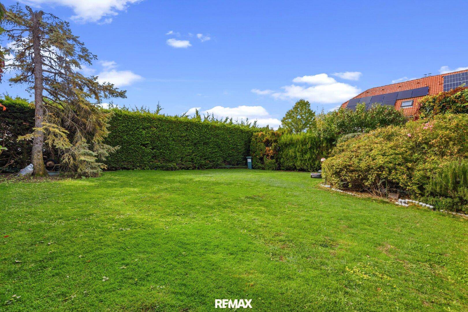 Großer, gepflegter Garten mit Rasenfläche und hohen Hecken für Privatsphäre.