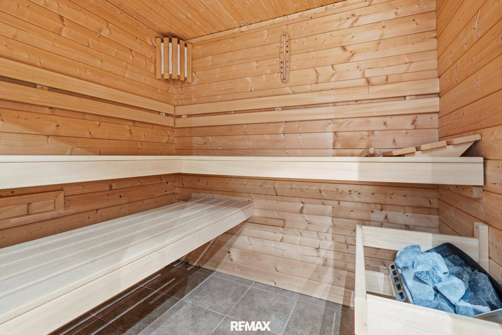 Moderne Holzsauna mit Bänken und Heizofen für entspannende Momente.