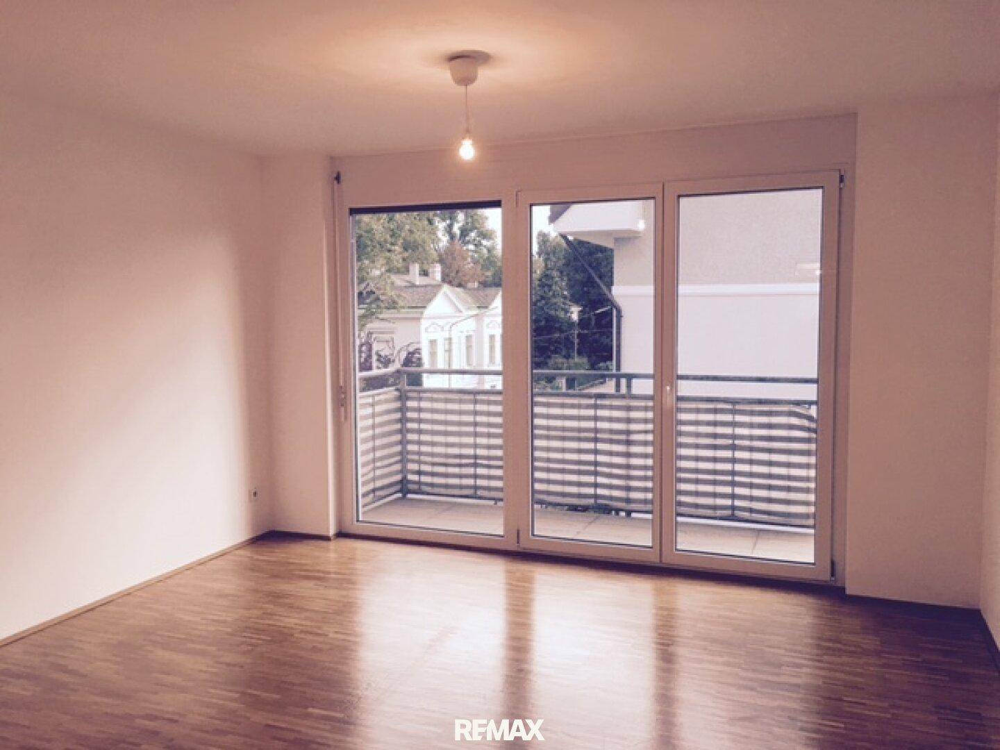 Heller Wohnraum mit Parkettboden und direktem Zugang zu einem Balkon.