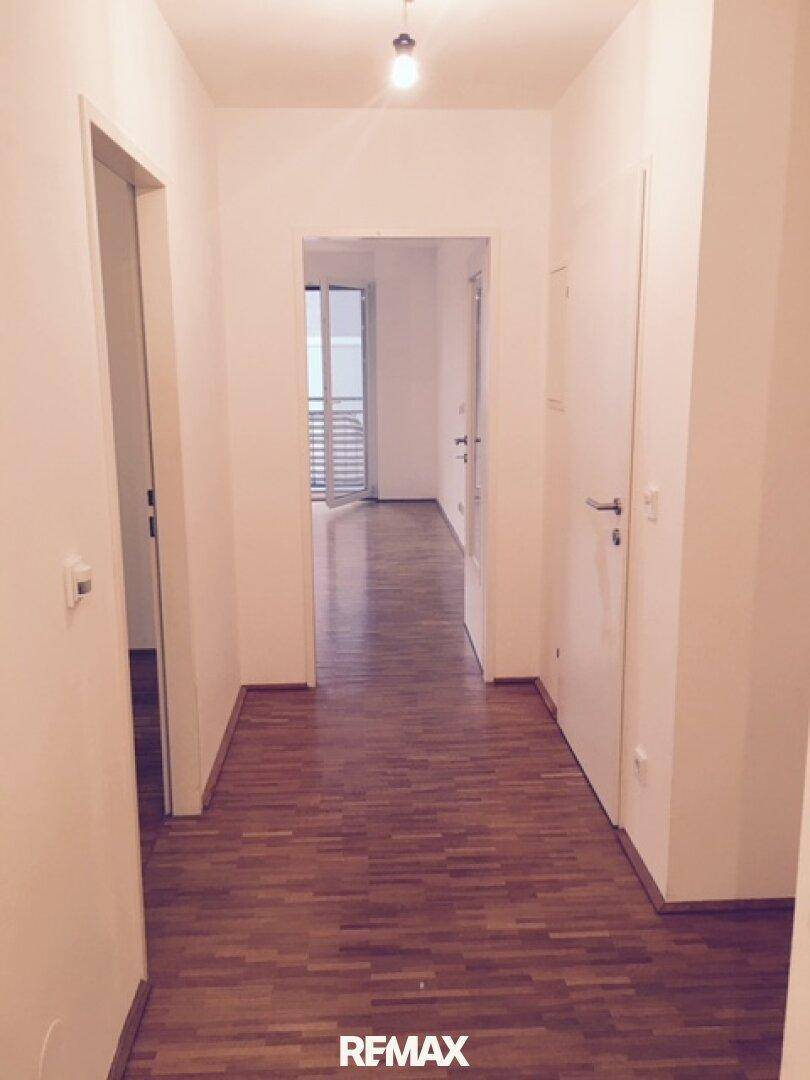 Langer Flur mit Parkettboden, der zu den verschiedenen Räumen der Wohnung führt.