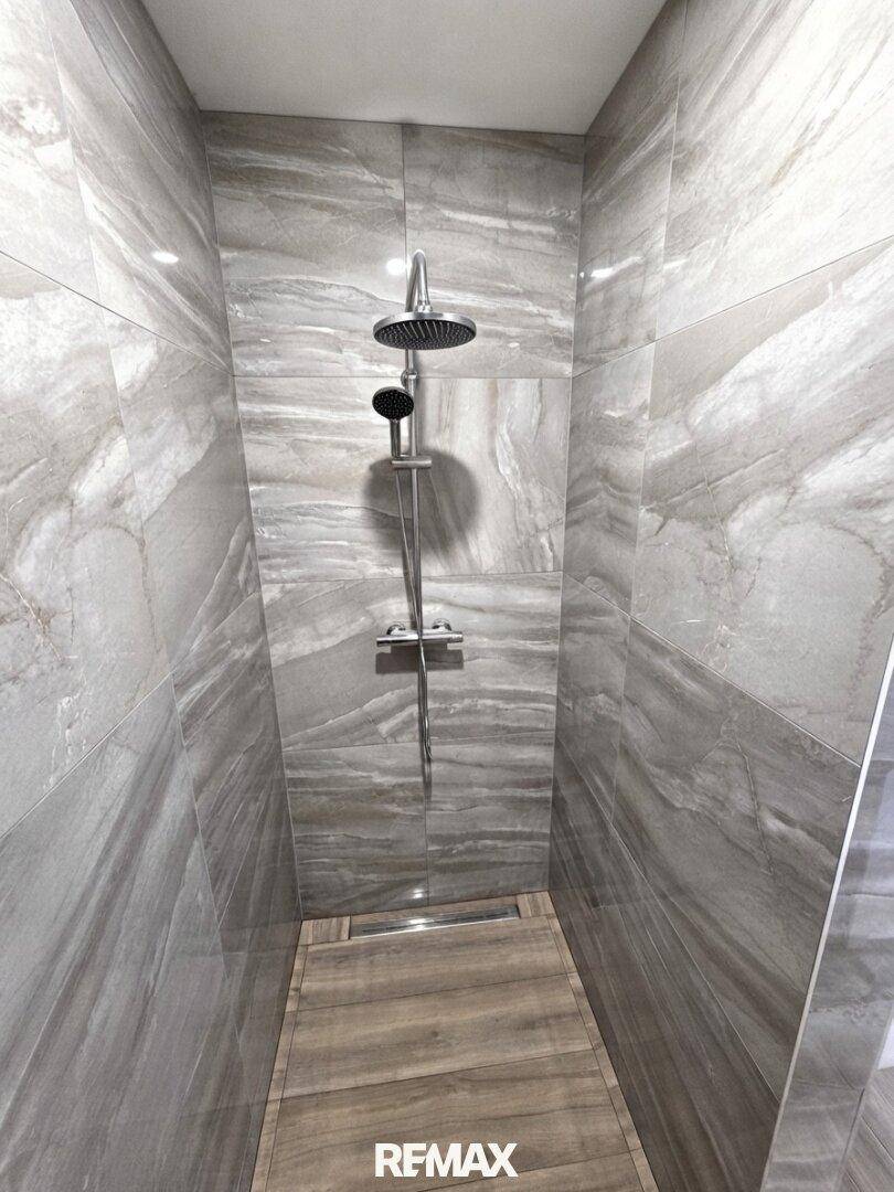 Moderne begehbare Dusche mit großformatigen Fliesen und Regendusche, elegant gestaltet.