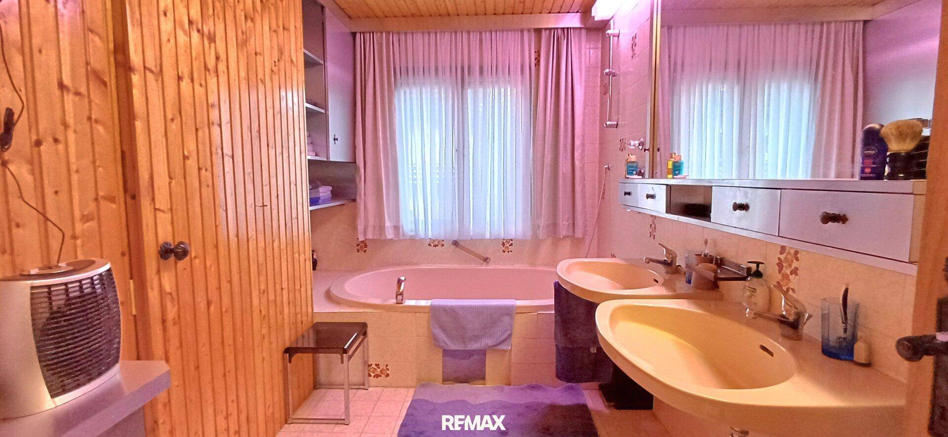 Badezimmer mit Holzverkleidung, Eckbadewanne und Doppelwaschbecken im rustikalen Stil.