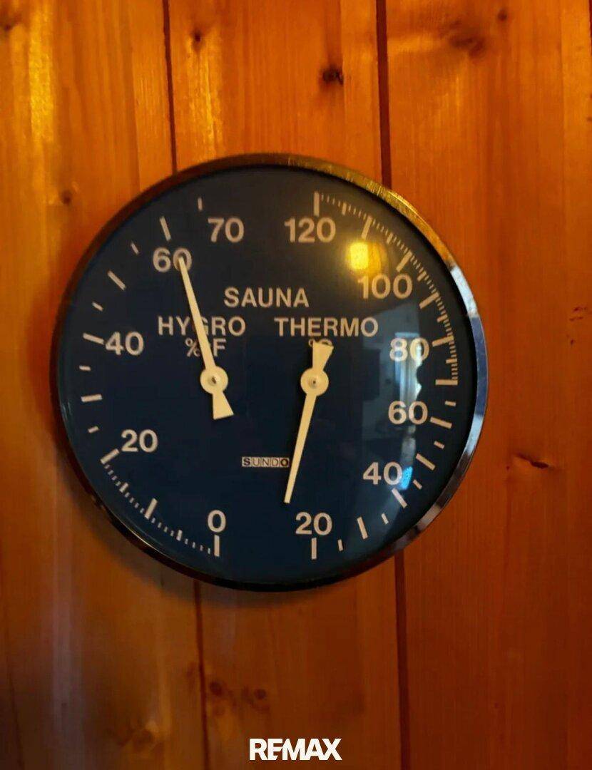 Nahaufnahme eines Sauna-Hygro-Thermometers an einer Holzwand, das die Temperatur anzeigt.