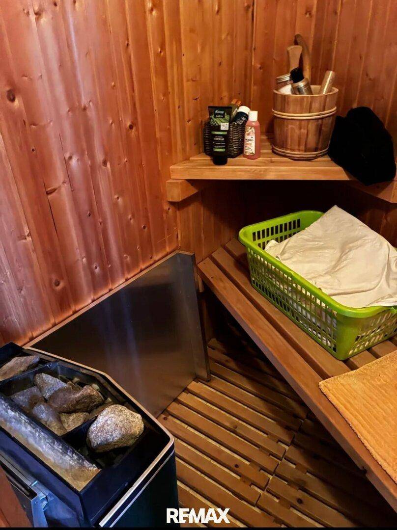 Saunakabine mit Holzverkleidung, Heizofen mit Saunasteinen und bequemen Holzbänken für Entspannung.