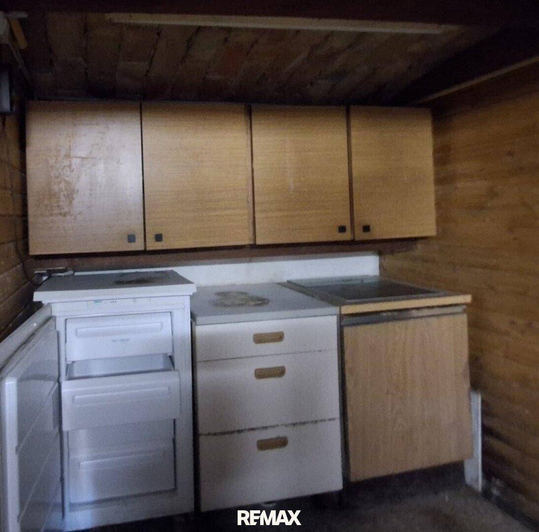 Einfacher Wirtschaftsraum mit Schränken und einem kleinen Kühlschrank, funktional eingerichtet.