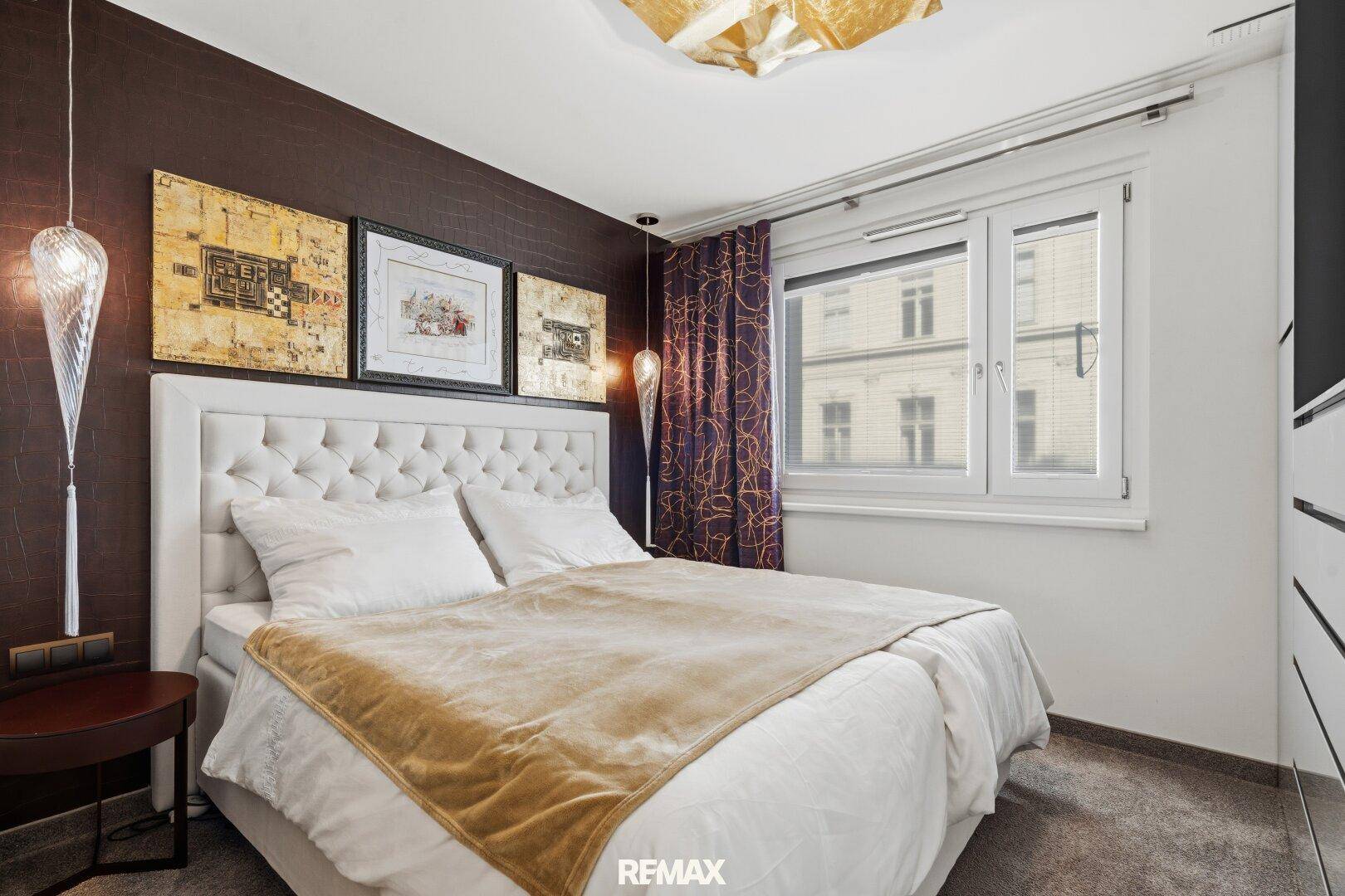 Helles Schlafzimmer mit großem Doppelbett, dunkler Akzentwand und Fenster.