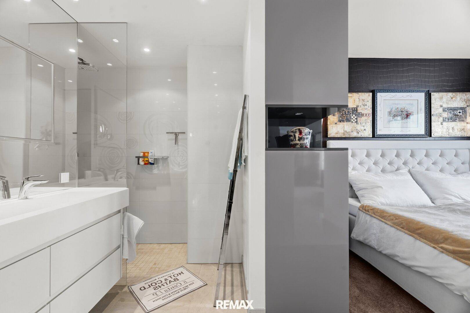 Offener Übergang vom Schlafzimmer zum modernen Badezimmer mit Duschbereich.
