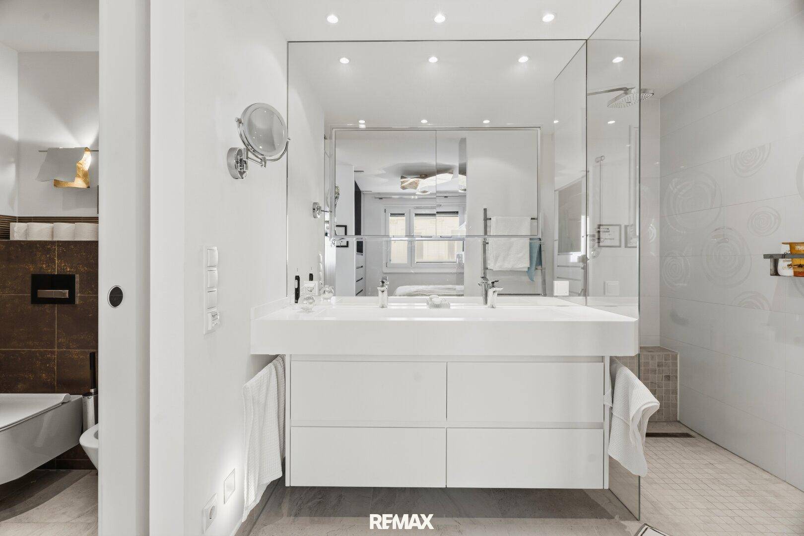 Modernes Badezimmer mit Doppelwaschbecken, großem Spiegel und Einbauschränken.