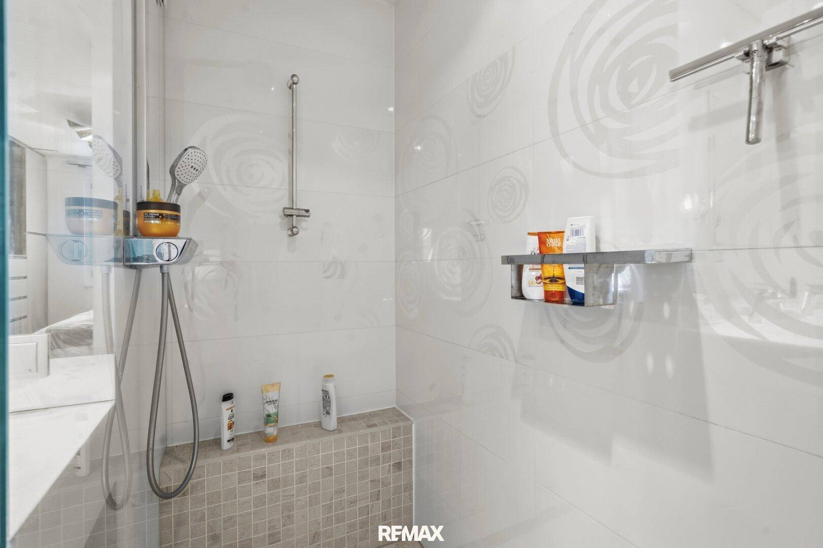 Geräumige begehbare Dusche mit modernen Fliesen und Duschkopf.