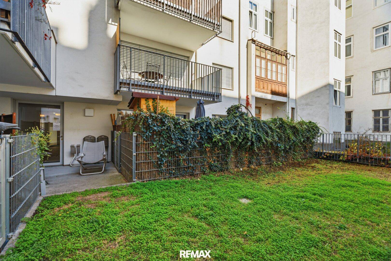 Kleiner Gartenbereich mit Rasenfläche, Terrasse und Sitzgelegenheit.
