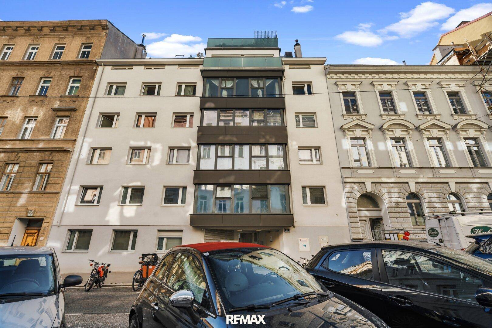 Mehrstöckiges Wohngebäude mit moderner Fassade und Balkonen in urbaner Umgebung.