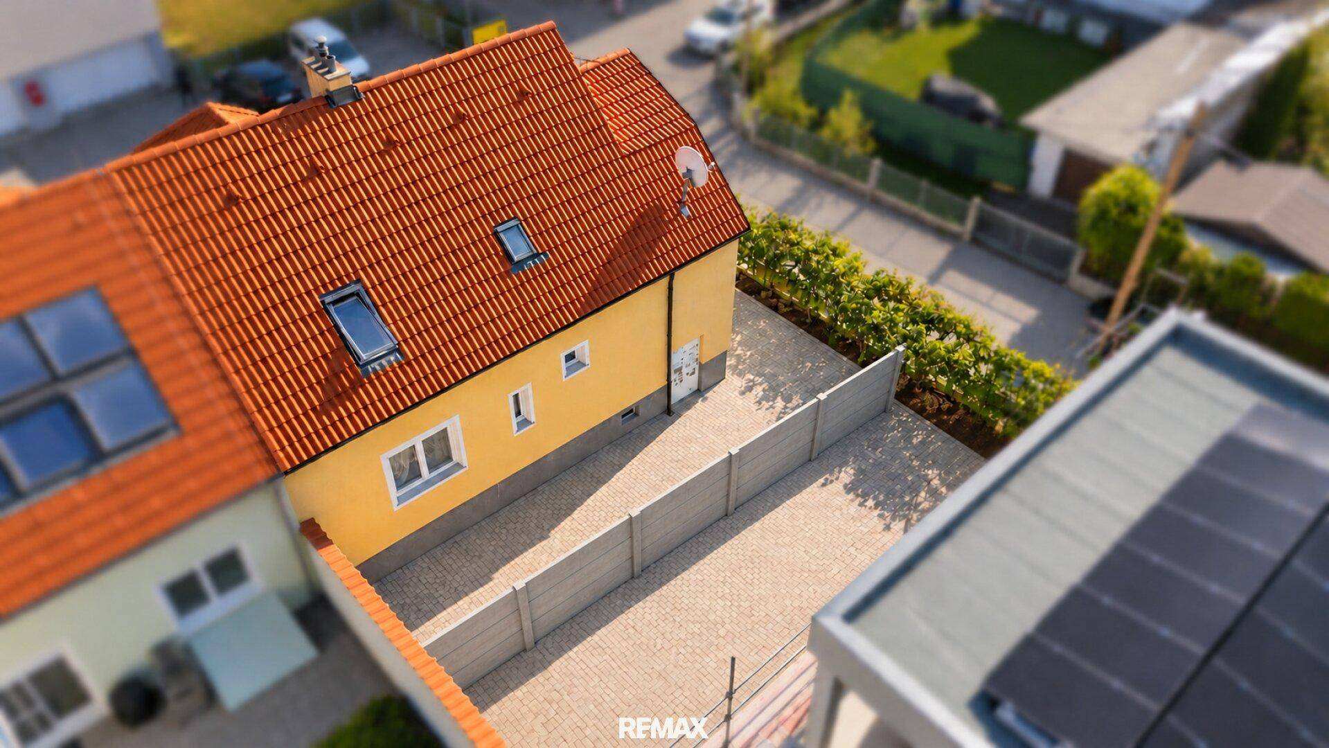 Dachansicht des Hauses mit Ziegeln, Dachfenstern und gepflastertem Zufahrtsbereich.