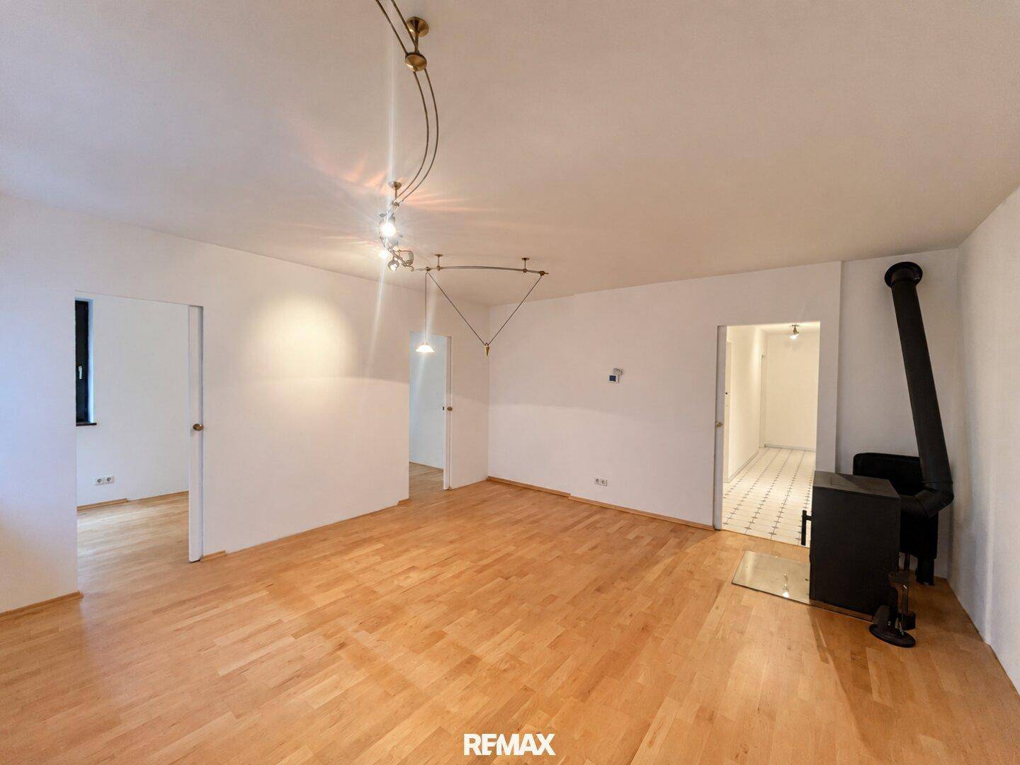 Geräumiges Wohnzimmer mit Holzofen und Parkettboden, bereit zur individuellen Gestaltung.