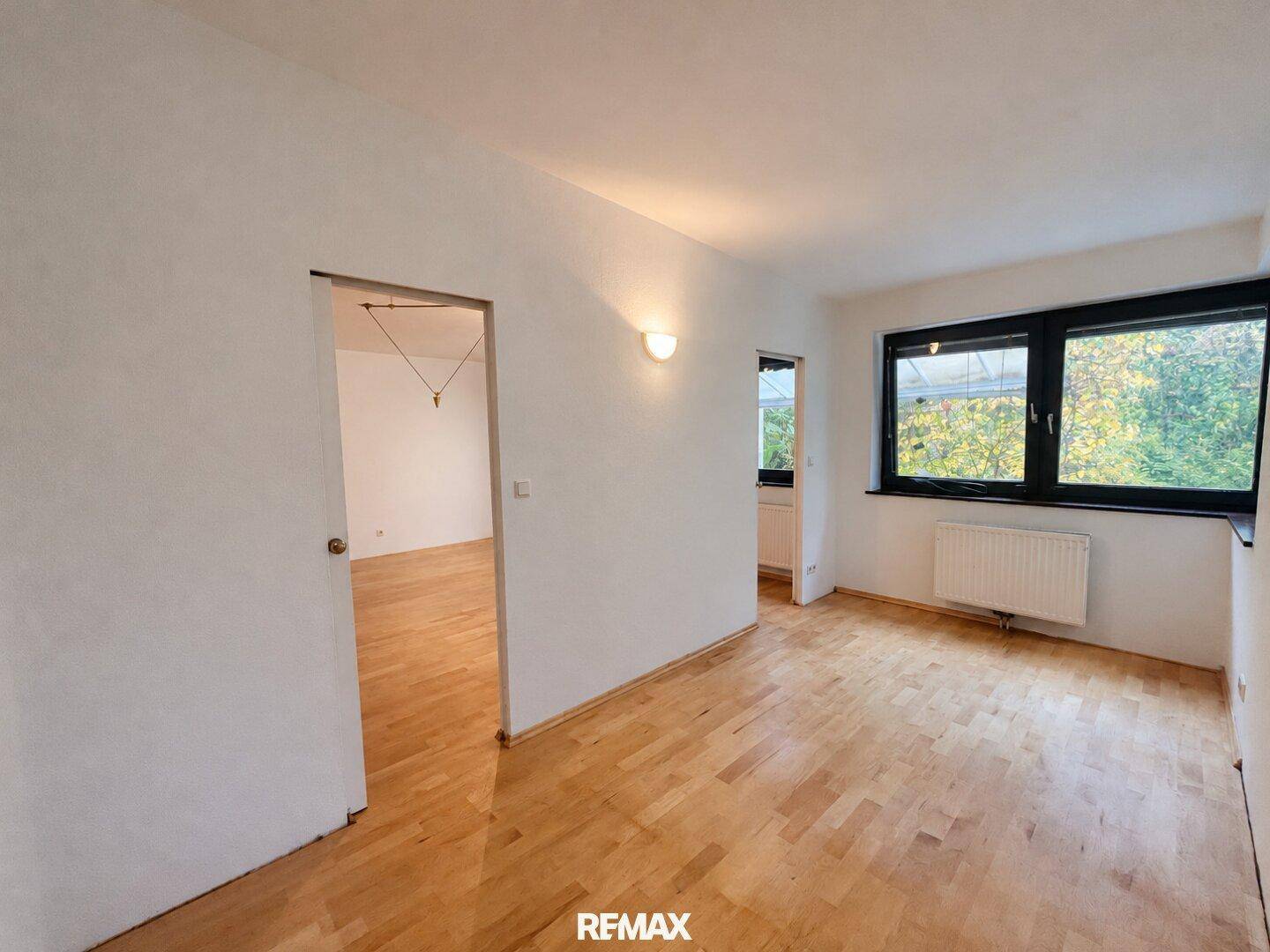 Helles Zimmer mit Parkettboden und Fenster, das viel Tageslicht hereinlässt.