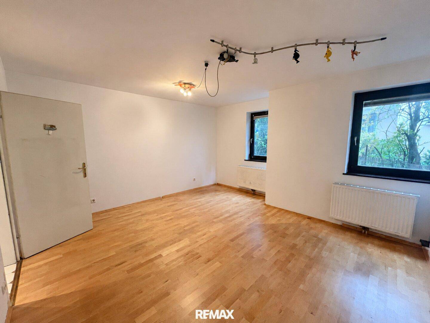 Schlafzimmer mit Parkettboden und zwei Fenstern, die für gute Belichtung sorgen.