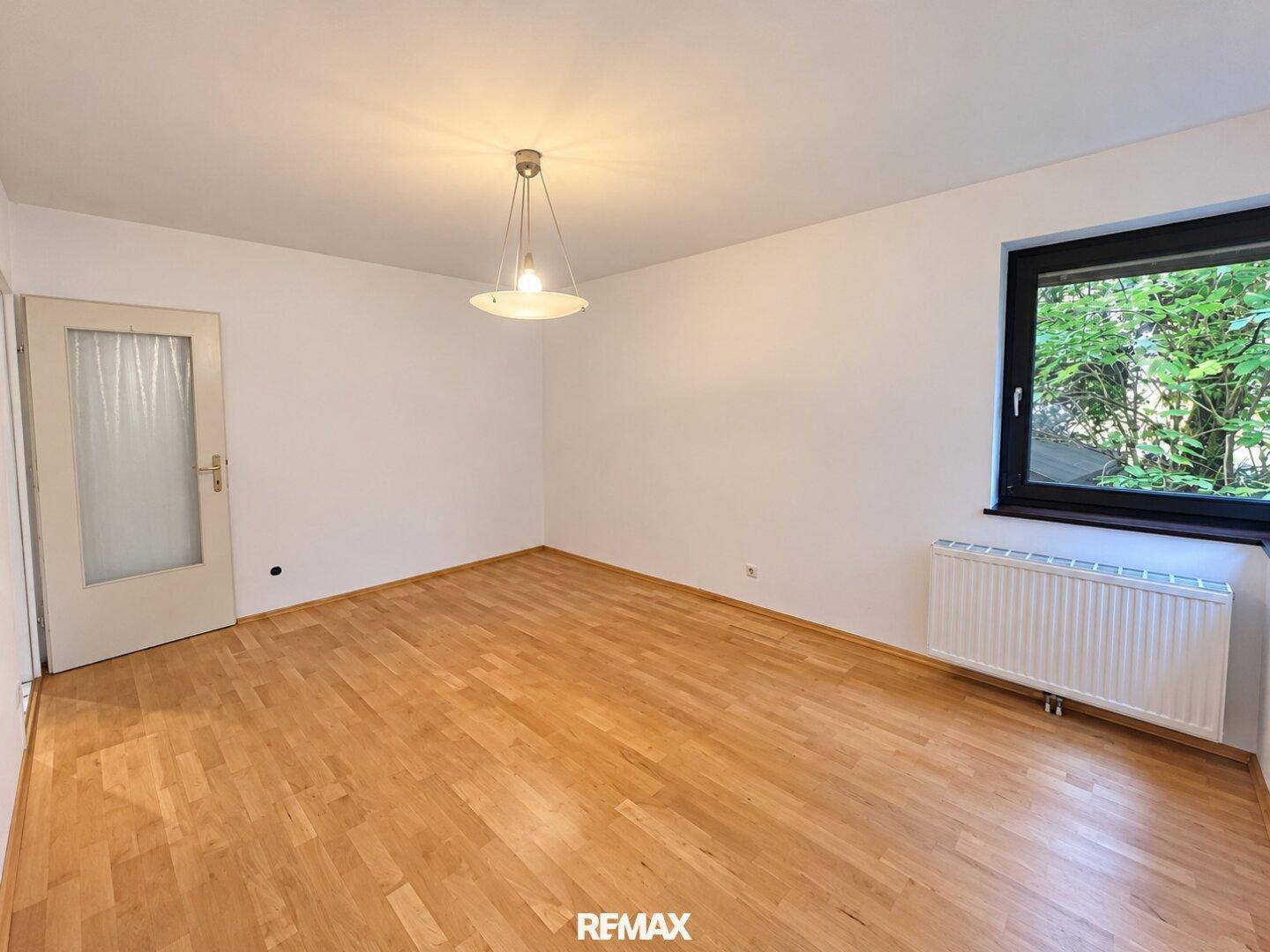Helles Zimmer mit Parkettboden und großem Fenster, ideal als Schlaf- oder Arbeitszimmer.