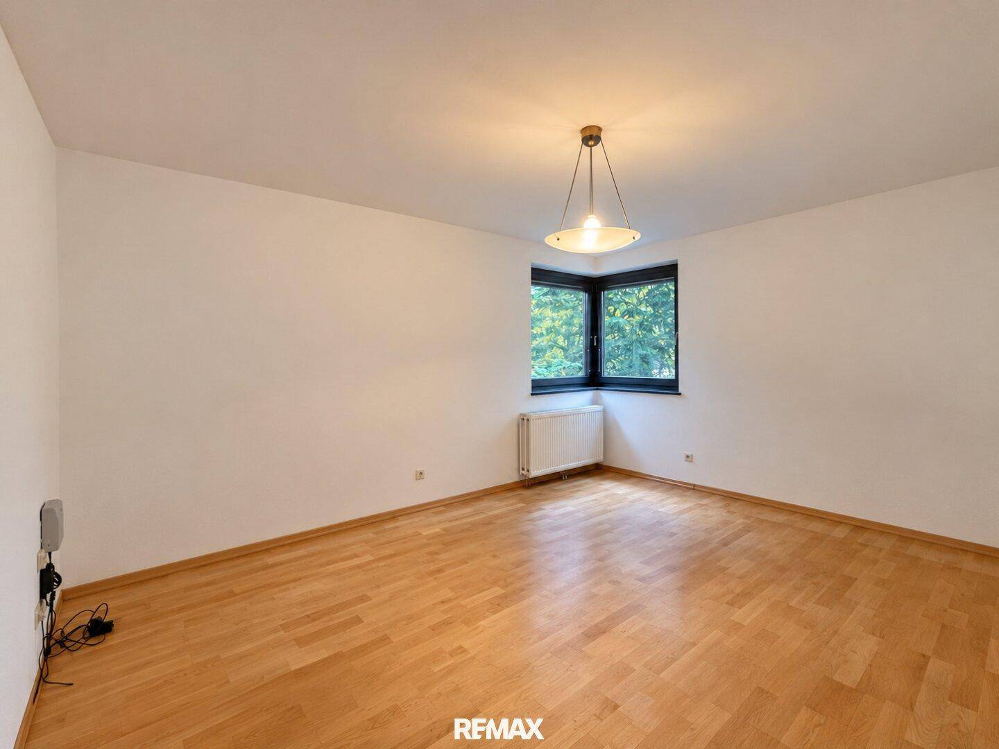 Geräumiges Zimmer mit Parkettboden und Eckfenster, das viel Licht bietet.