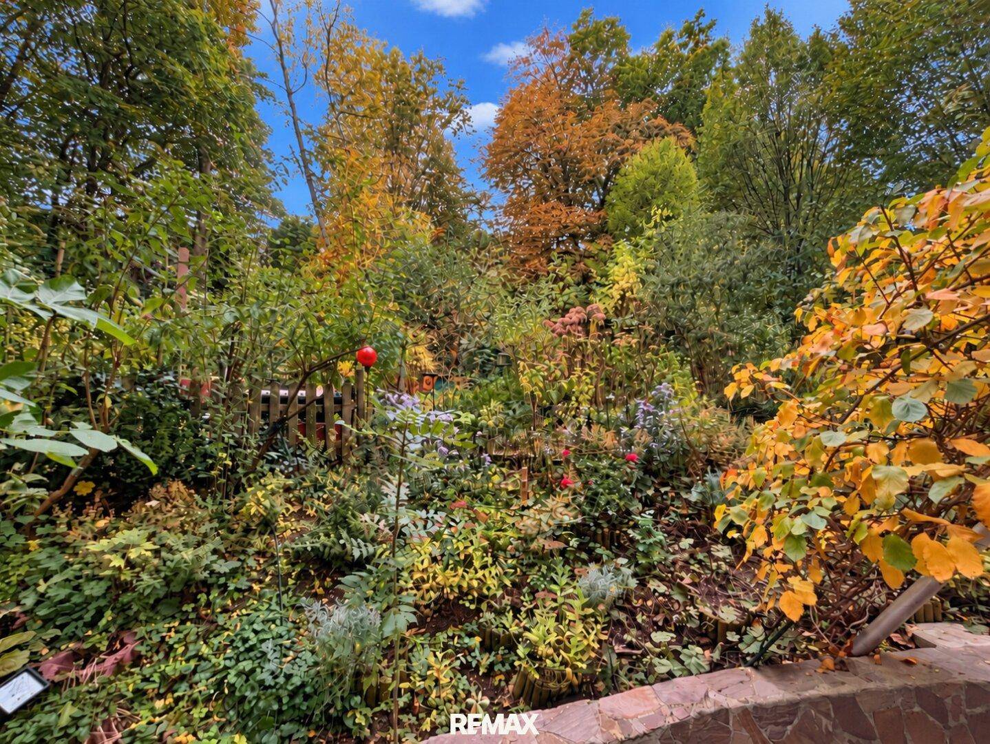 Üppiger Garten mit vielfältigen Pflanzen und herbstlicher Färbung, ideal zum Entspannen.