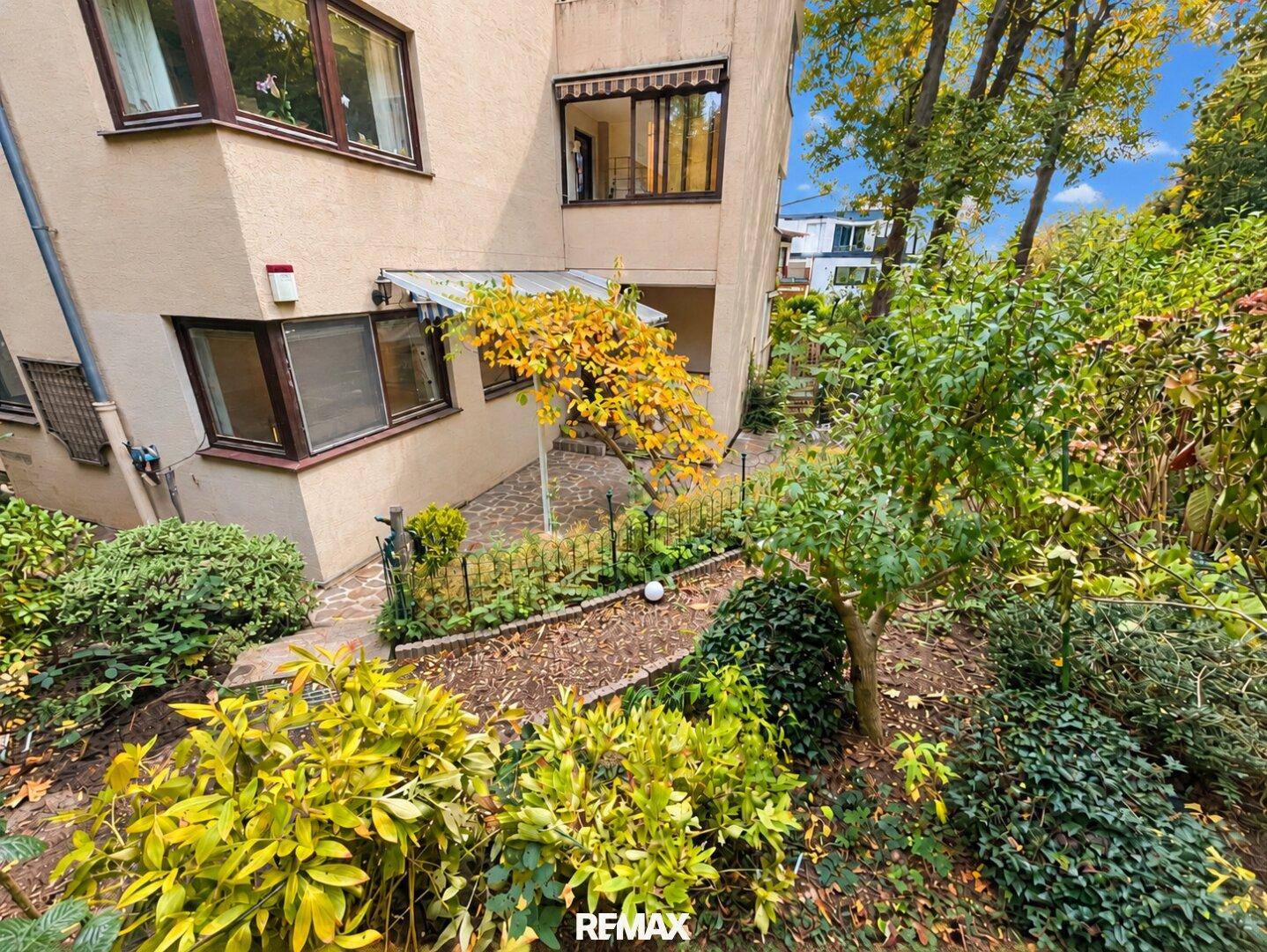 Gartenbereich mit Wegen und üppiger Vegetation, die zum Gebäude führen.