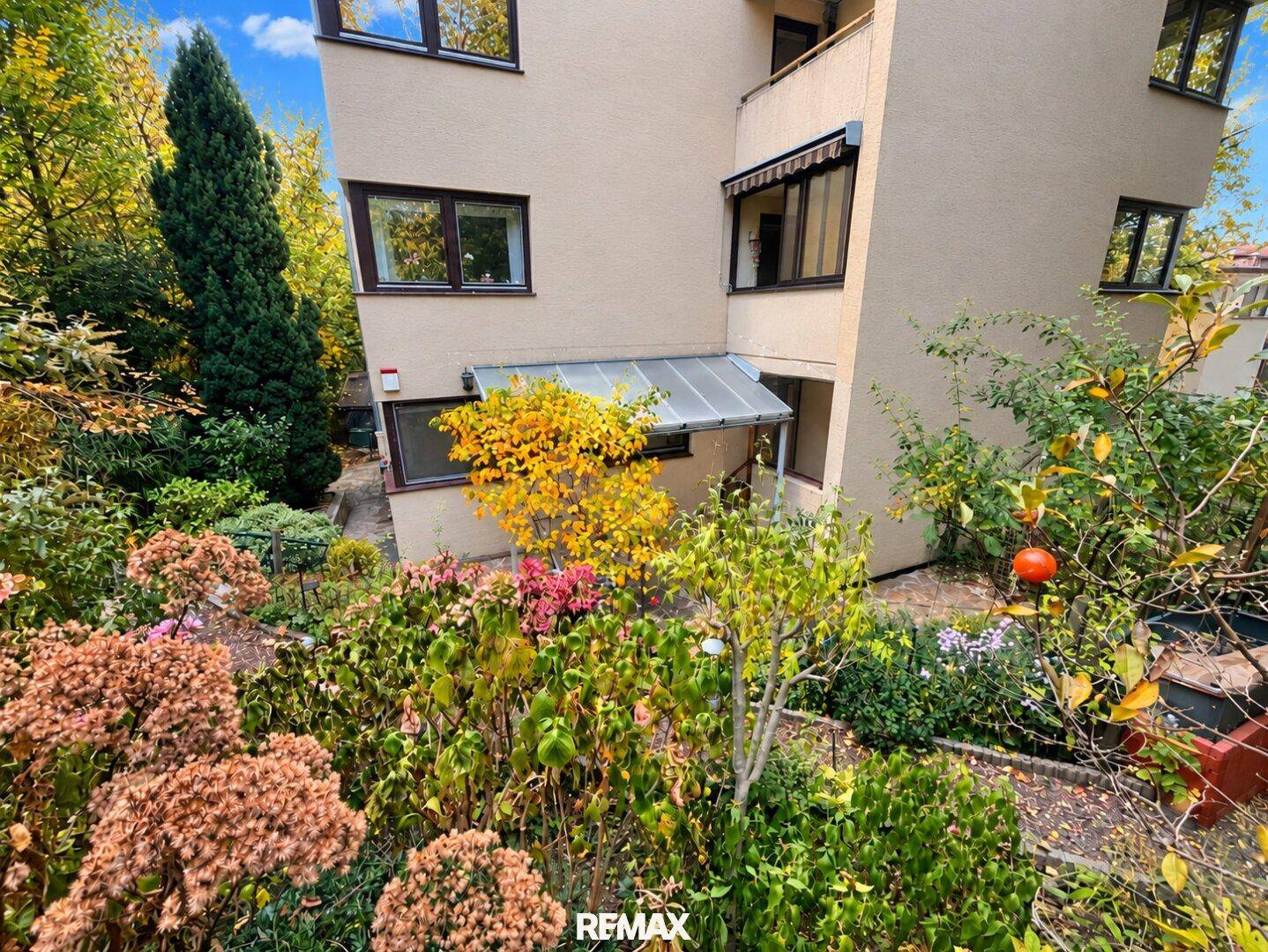 Gepflegter Garten mit vielfältiger Bepflanzung und Blick auf die Gebäudeseite.