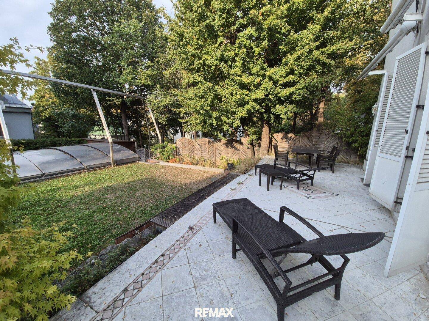 Großer Gartenbereich mit überdachtem Pool, Liegestühlen und Essbereich im Freien.