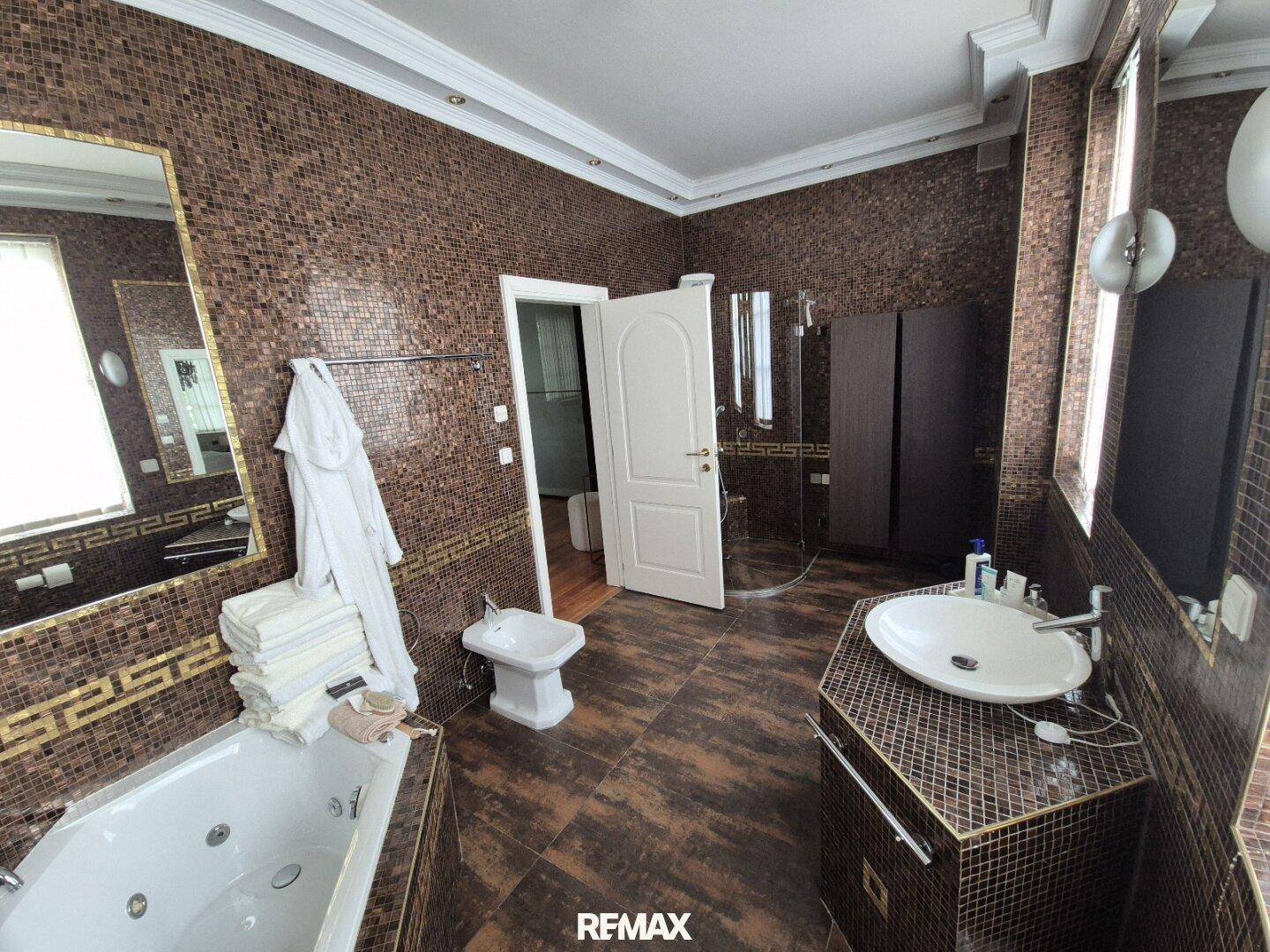 Luxuriöses Badezimmer mit Mosaikfliesen, Whirlpool-Badewanne, Bidet und Doppelwaschbecken.