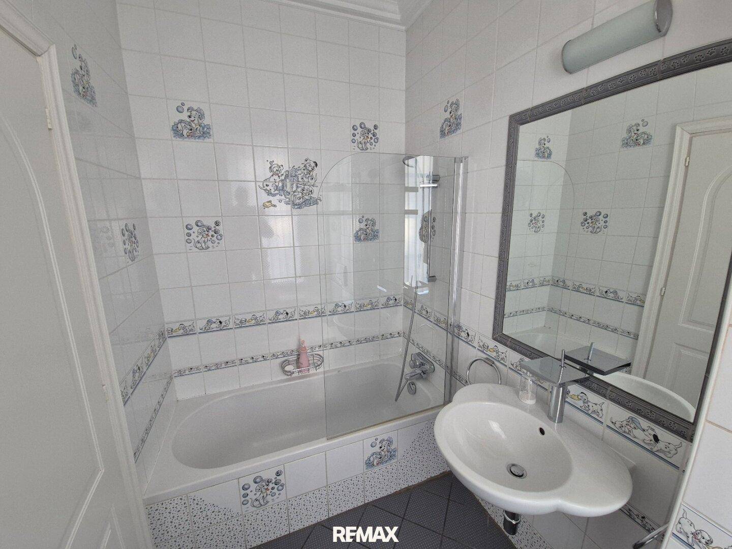 Helles Badezimmer mit Badewanne, Duschabtrennung und verspielten Fliesen.