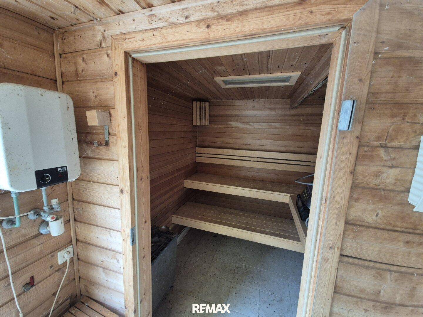 Gemütliche Holzsauna mit Sitzbänken und traditionellem Saunaofen für Entspannung.