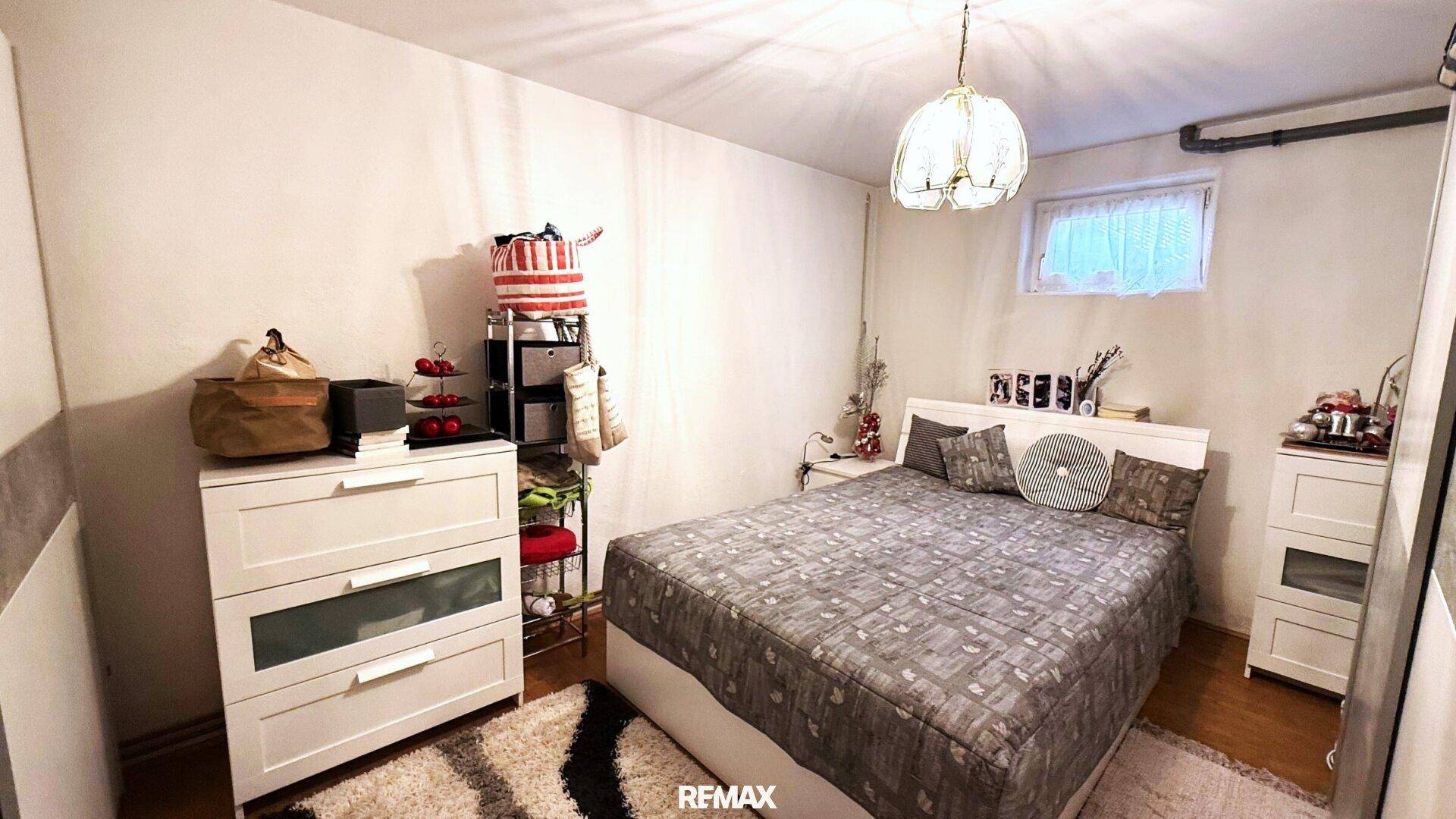 Schlafzimmer im Untergeschoss mit Doppelbett, Kommode und kleinem Fenster.