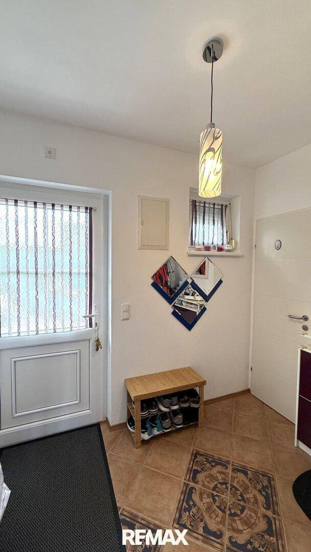 Eingangsbereich mit Terrakotta-Fliesen, Schuhbank und dekorativen Spiegeln an der Wand.